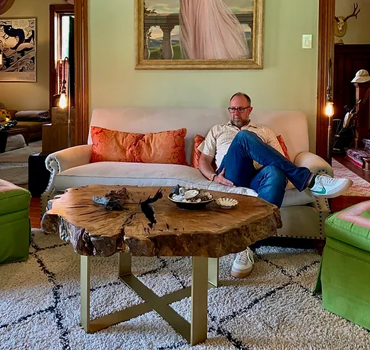 Live edge round coffee table with brass X-base in a Texas living room